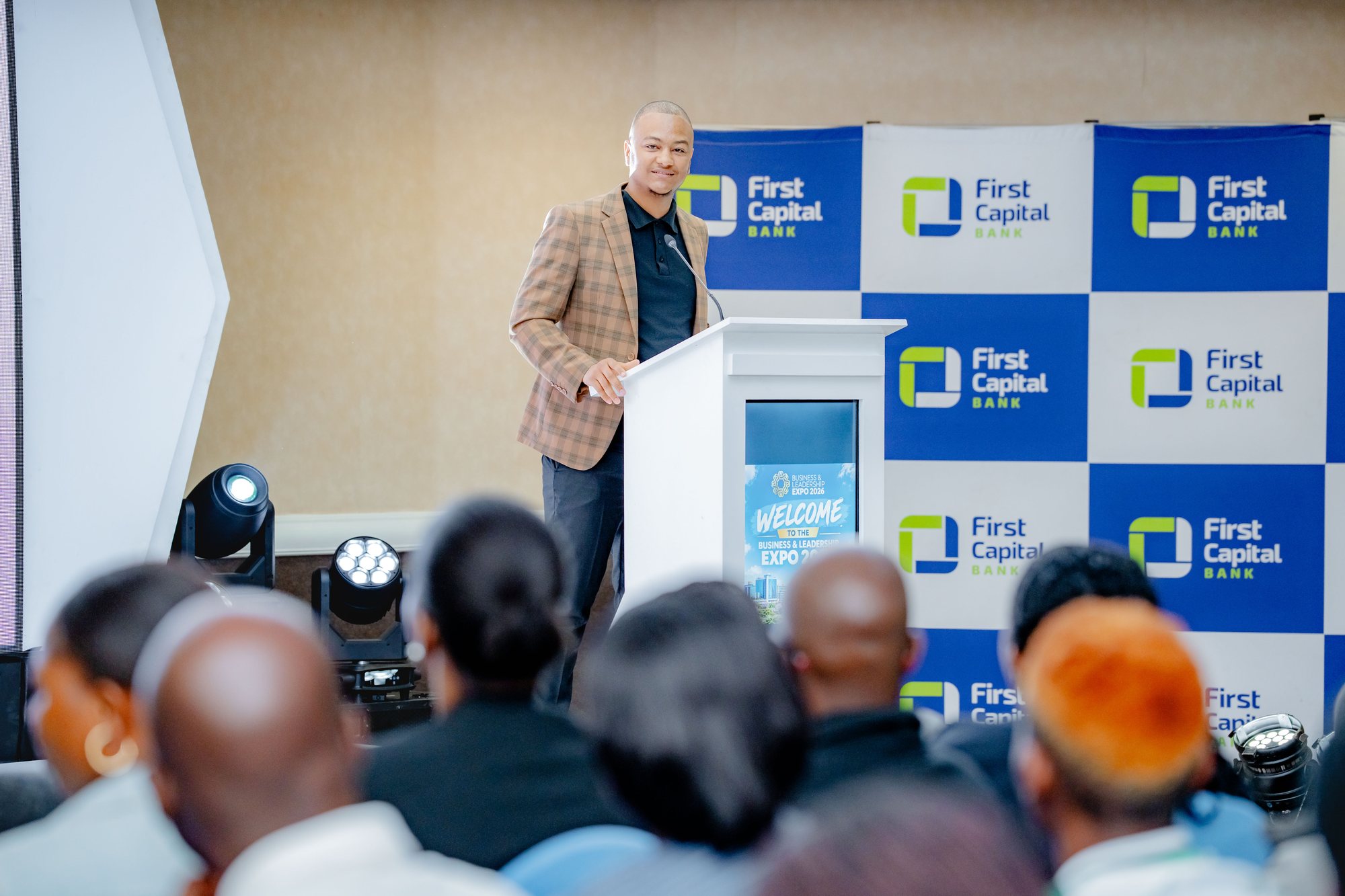 Maverick Kabelo speaking at a white lectern in front of a seated audience at the Business and Leadership Expo 2026